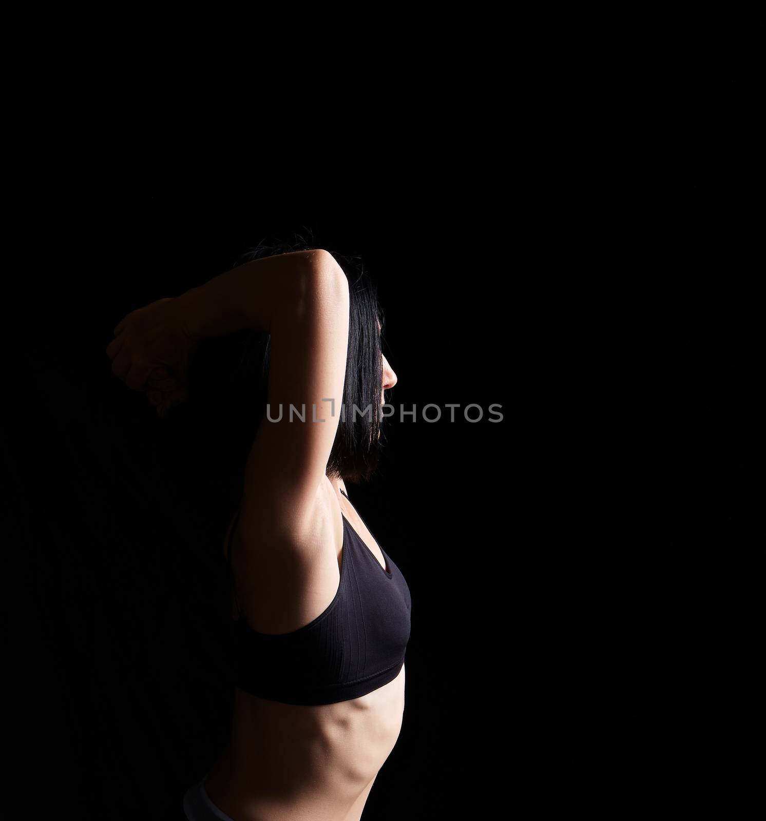 body of a girl of athletic appearance in a black bra, athlete stands sideways, low key