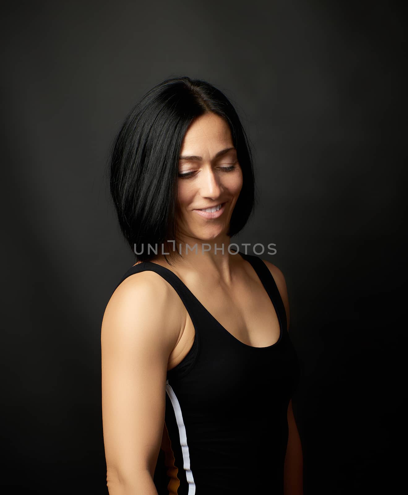 portrait of a beautiful young woman with black hair on a dark background, girl smiling