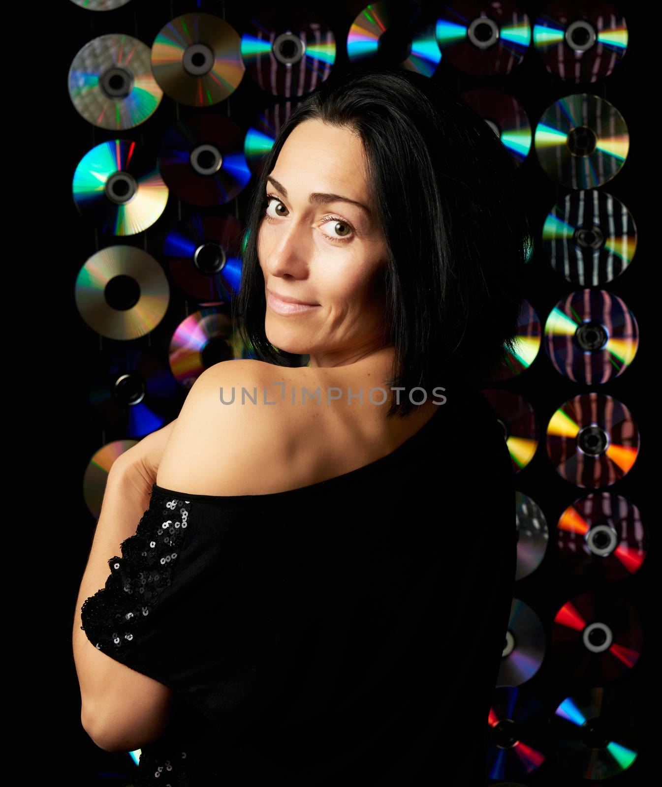 young Caucasian woman posing on a shiny flickering dark background, girl looking at the camera