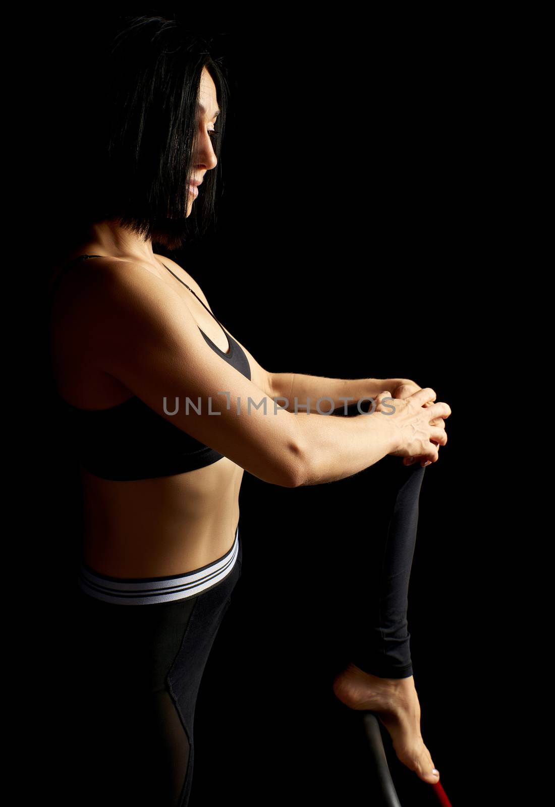 beautiful young woman with black hair and a muscular body sits, low key