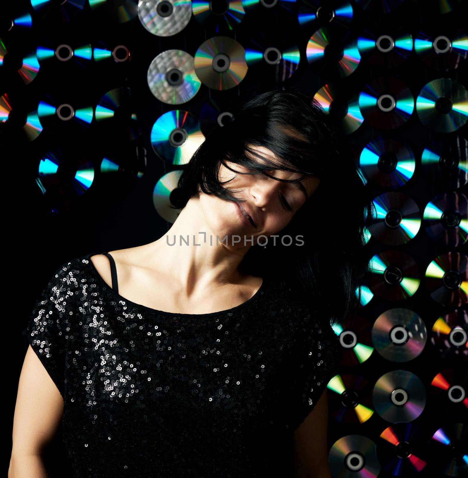 young woman of Caucasian appearance is dancing on a shiny flickering dark background, her hair is flying in different directions, the girl is smiling
