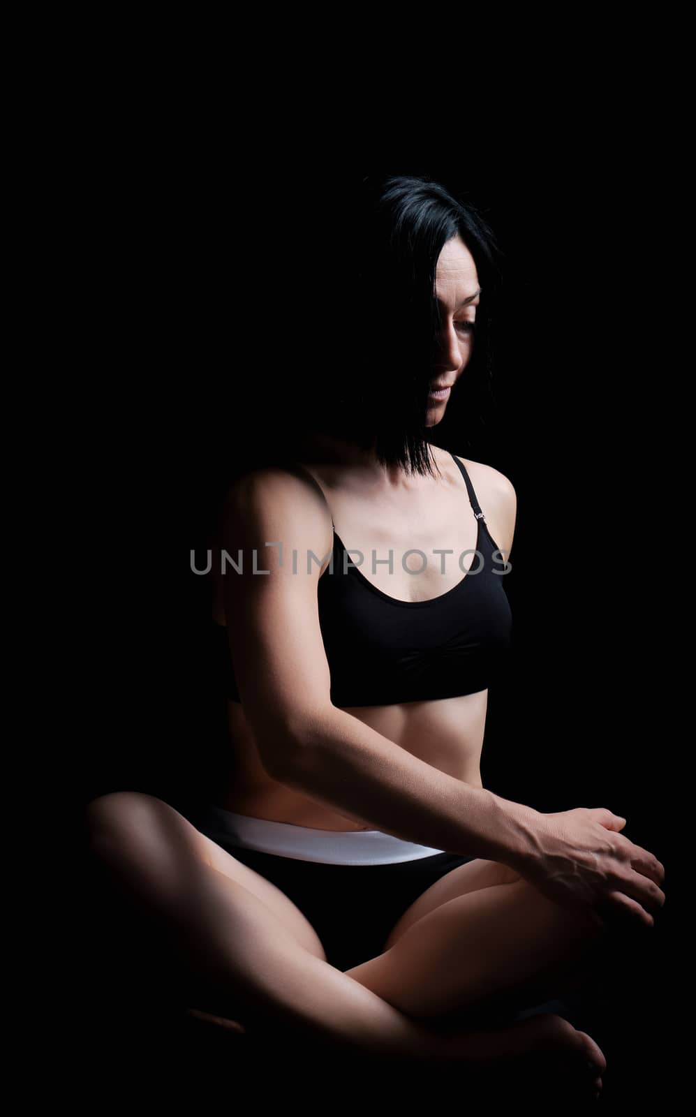 young girl of athletic appearance with black hair sits in a lotu by ndanko