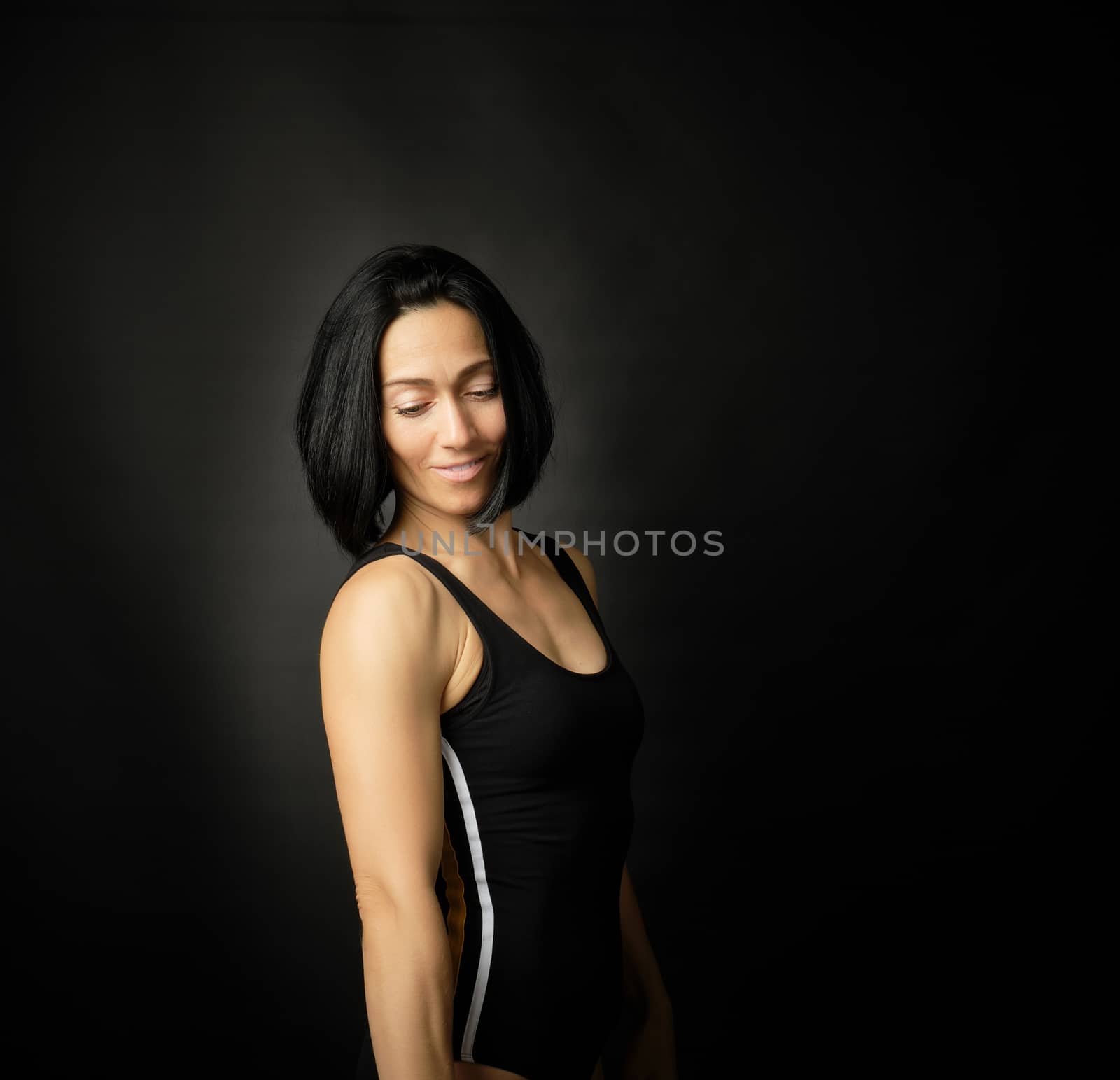 Adult girl with a sports figure standing on a dark background by ndanko