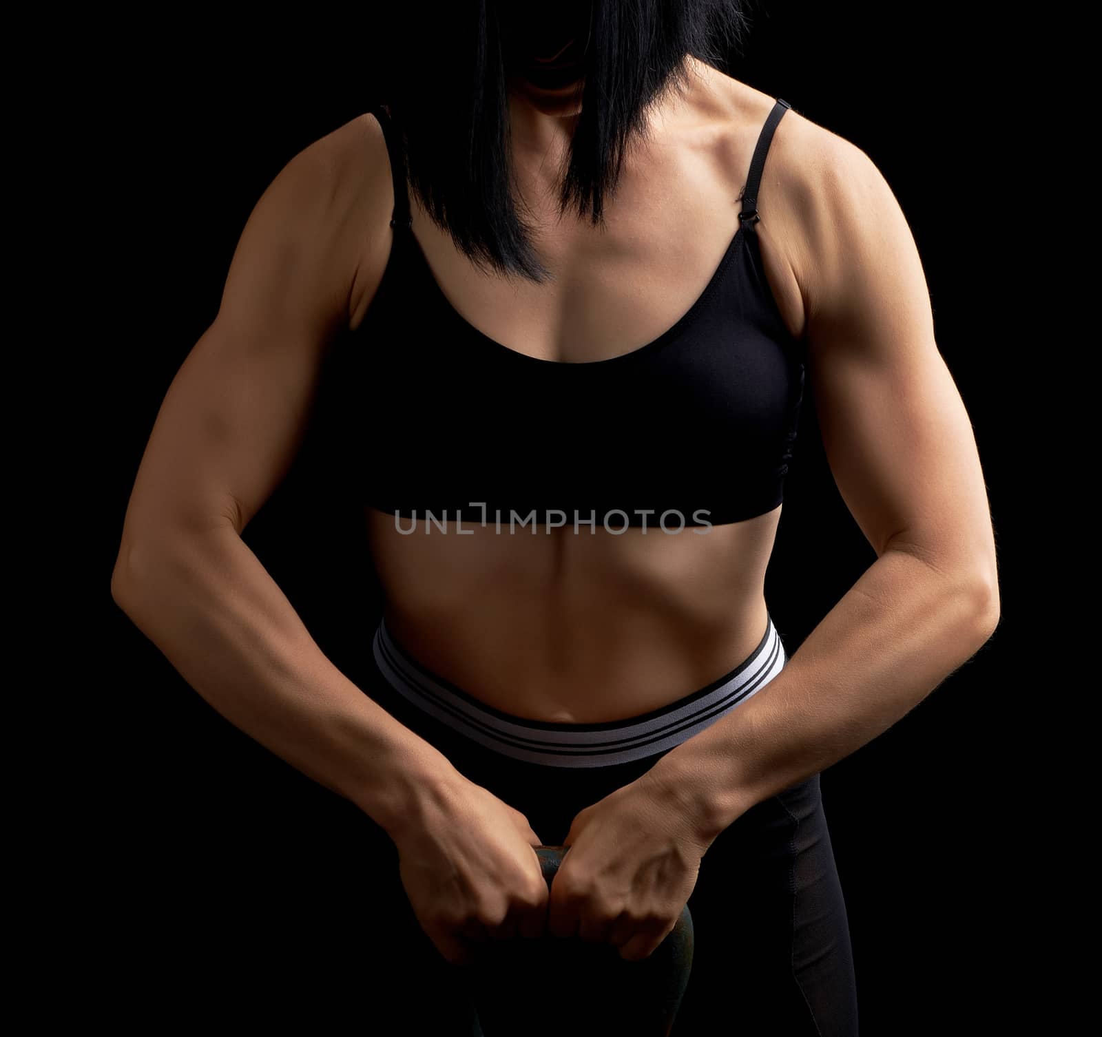 girl of athletic appearance holds an iron kettlebell in front of by ndanko