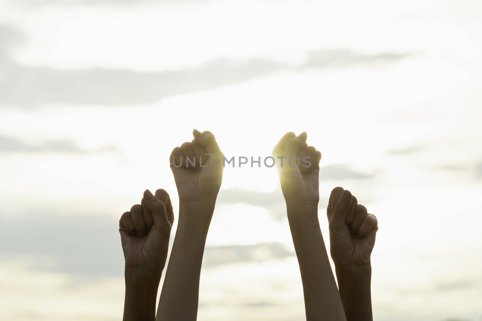 Hand of people fist raising up showing power strong with sky background.