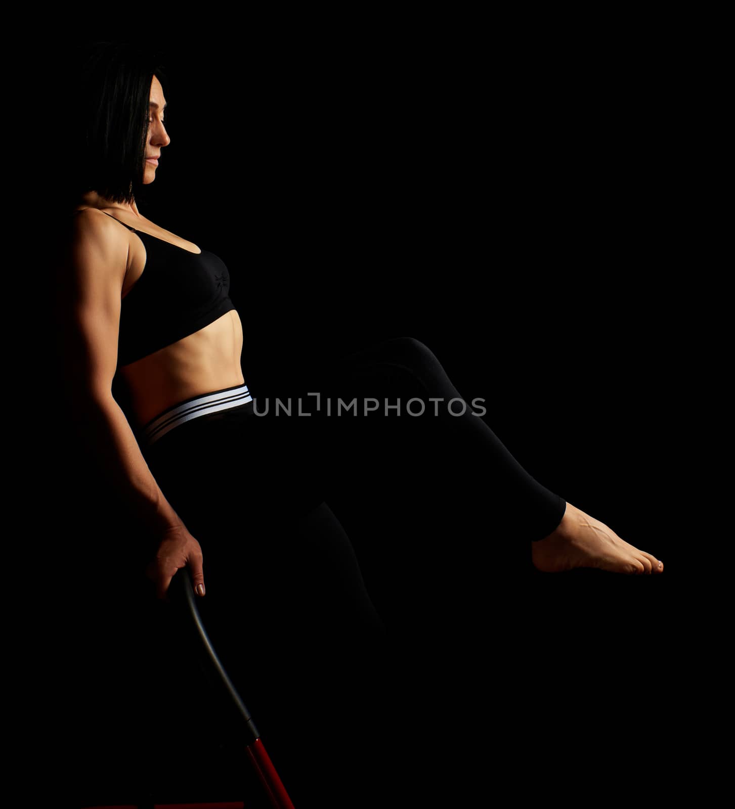 beautiful young woman with black hair and a muscular body sits o by ndanko