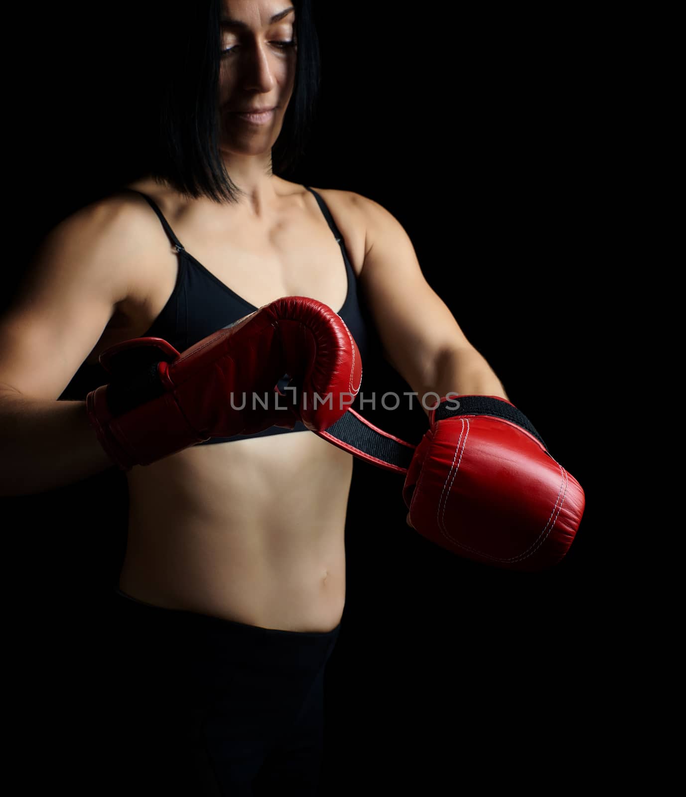 beautiful young girl of athletic appearance with black hair dresses red leather boxing gloves, low key