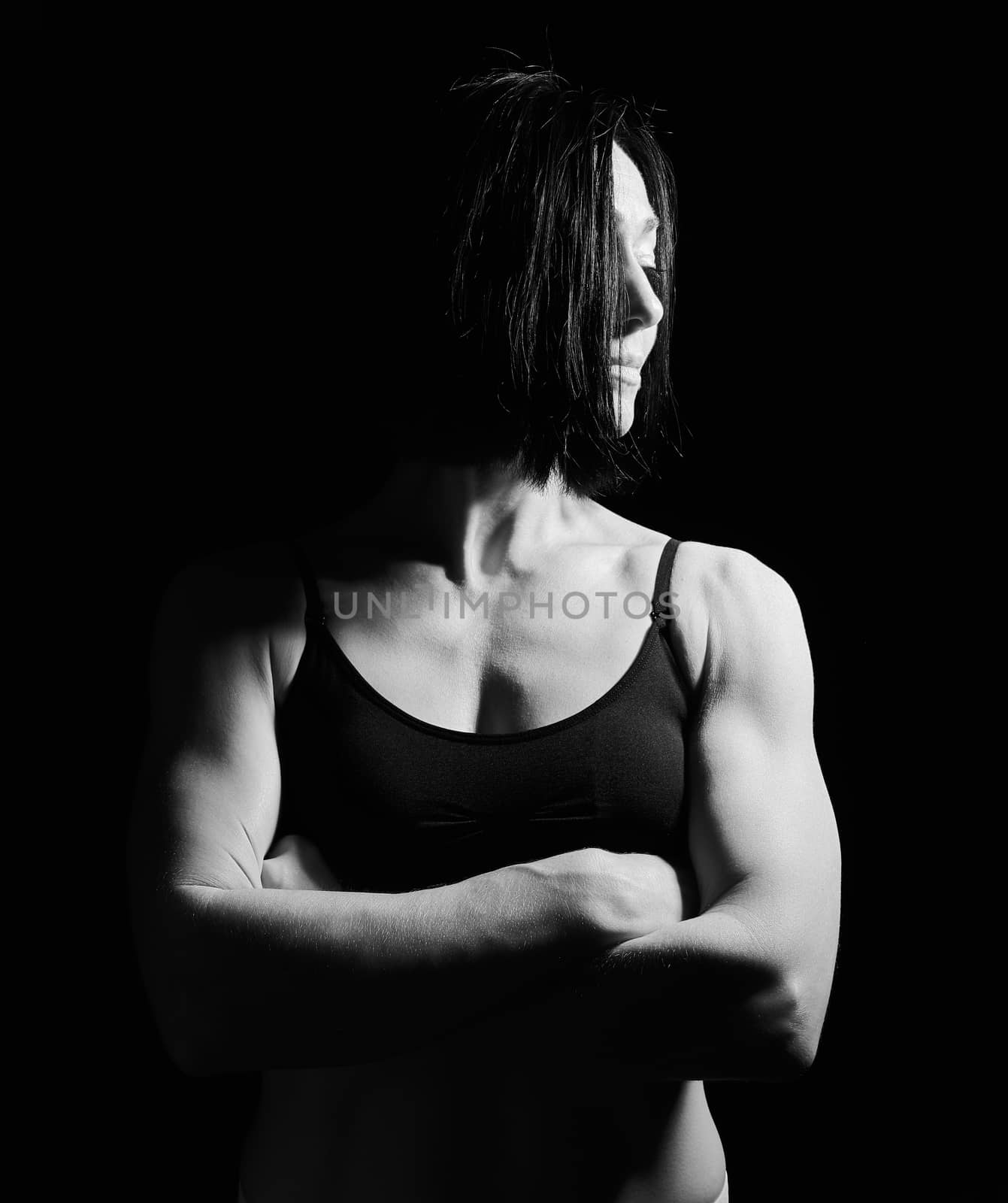 portrait of a beautiful athletic girl with black hair, her arms crossed on her chest, black and white toning