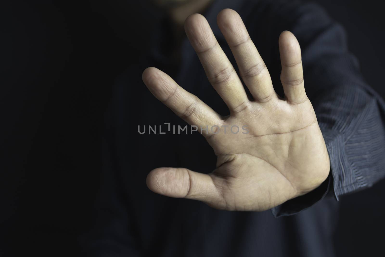 Show hand with stop gesture on black background. Man showing stop gesture.
