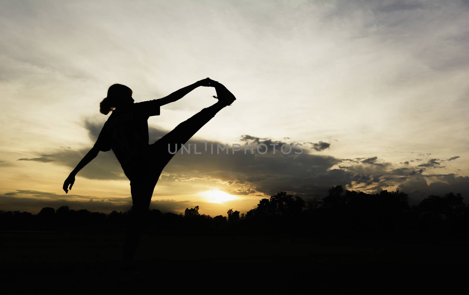 Silhouette of young woman practicing yoga outdoor. Female happin by kirisa99
