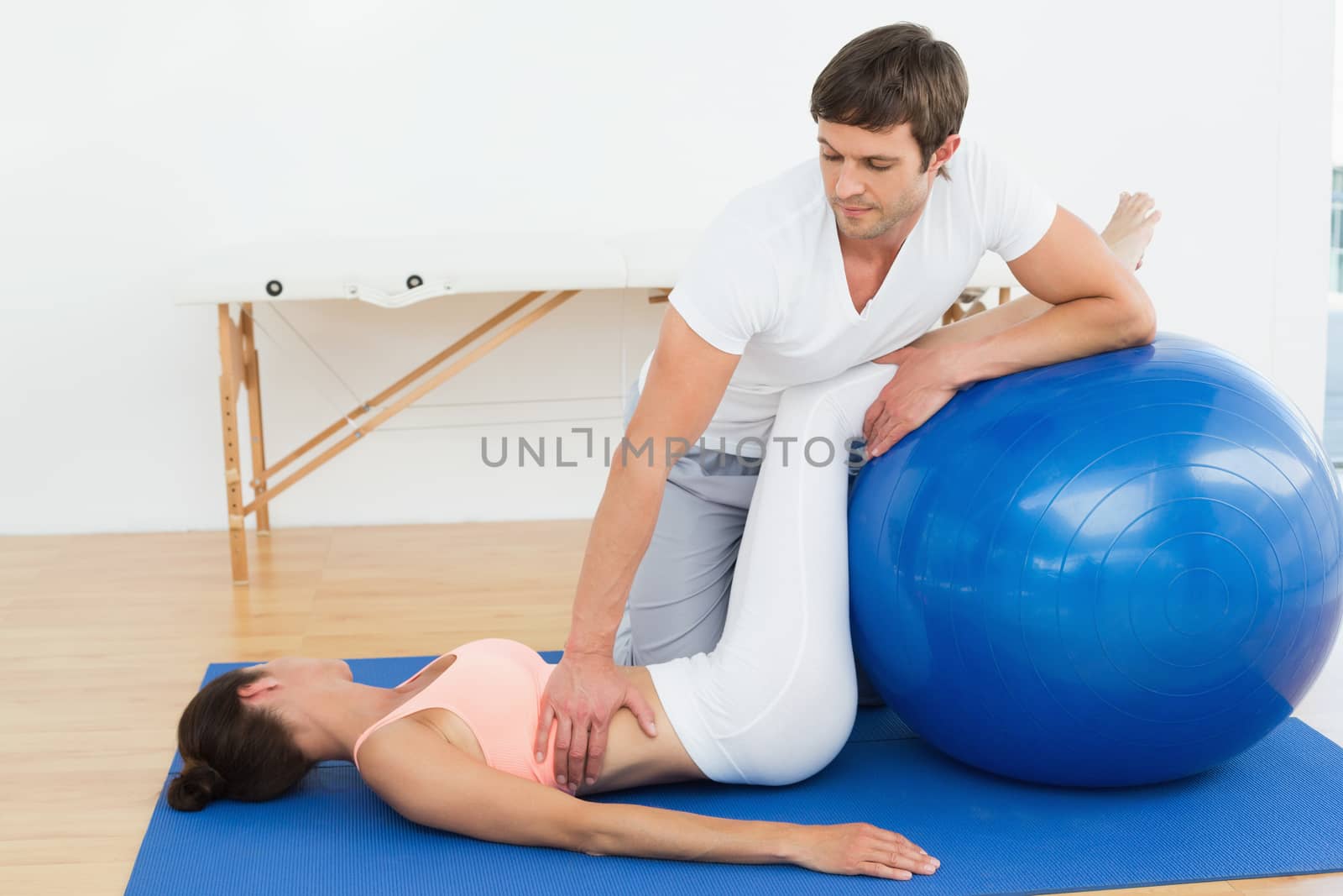 Physical therapist assisting woman with yoga ball by Wavebreakmedia