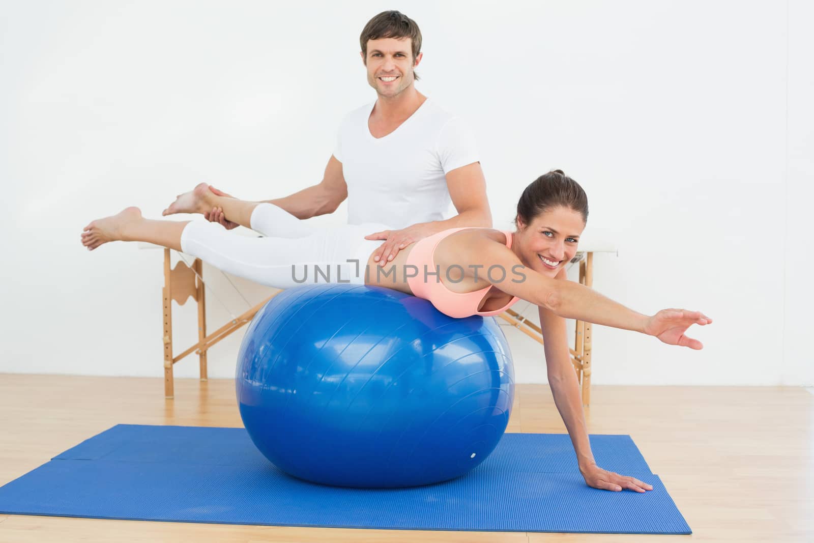 Physical therapist assisting woman with yoga ball by Wavebreakmedia