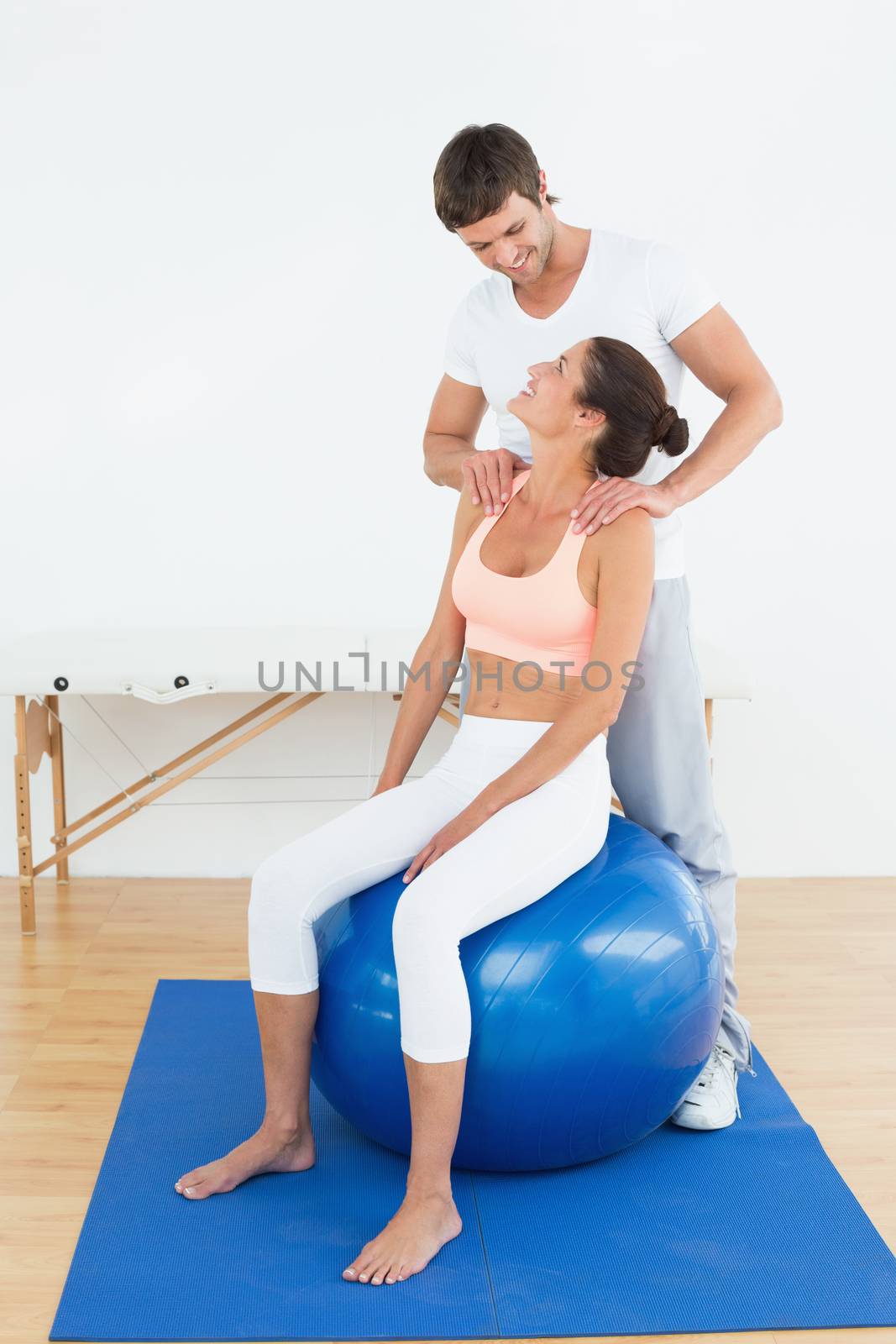 Young woman sitting on yoga ball while working with a physical therapist