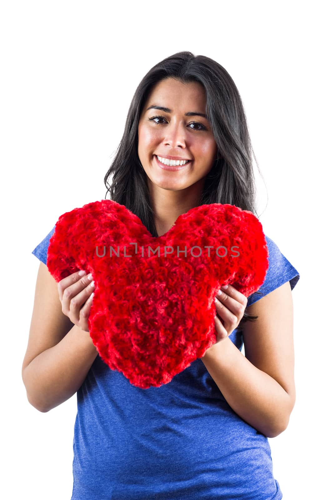 Smiling woman holding a heart shaped pillow by Wavebreakmedia