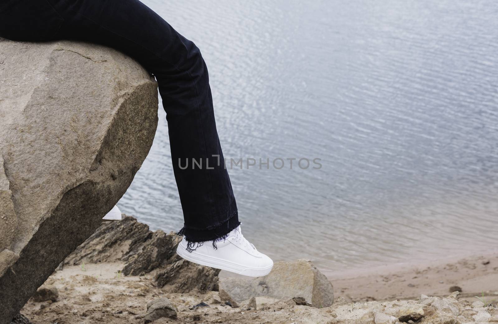 Girl resting on a rock. Woman sitting on rock near river.