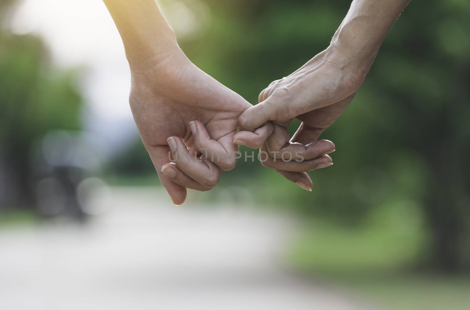 Hand of lady and younger lady holding together on blur background