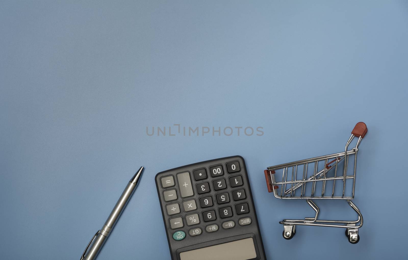 Black calculator with pen and shopping cart with copy space. Technology and financial concept.