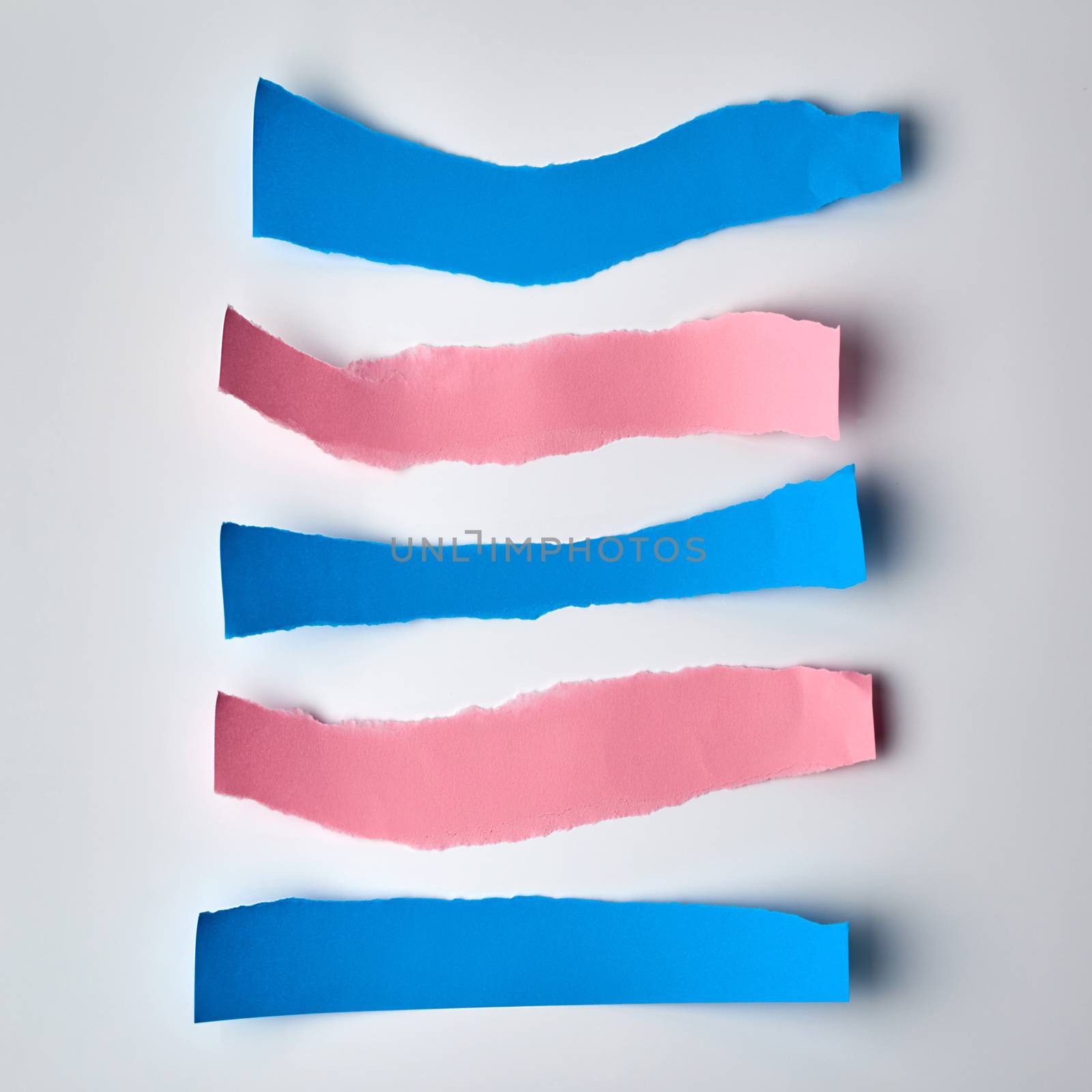 pink and blue torn strips of paper on a white background, flat lay