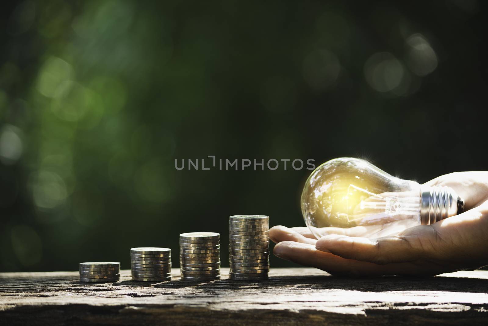 Hand of male holding a light bulb with stack of coins and copy s by kirisa99