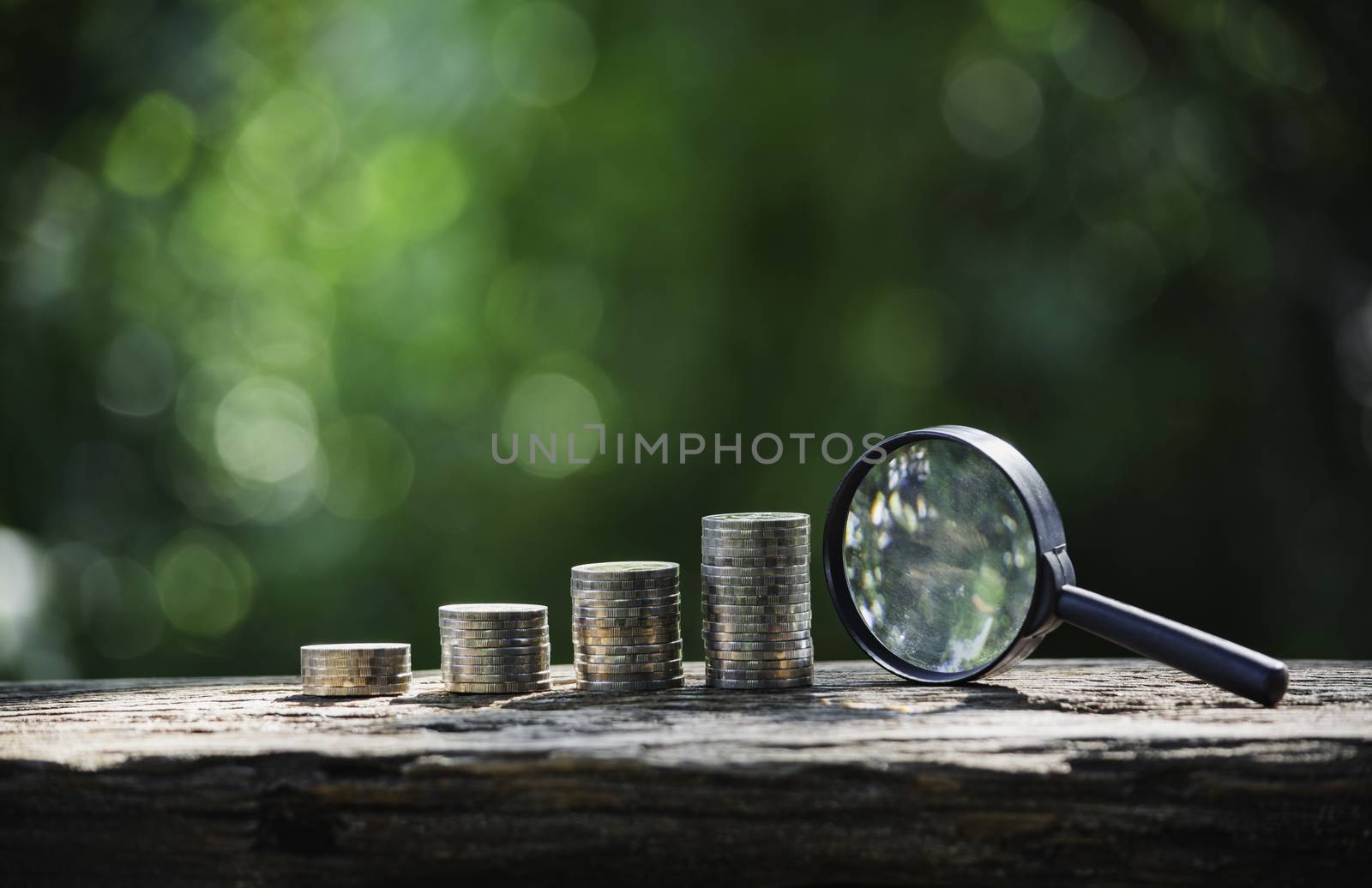 Saving money concept with money coin stack and magnifying glass. Financial and accounting concept.