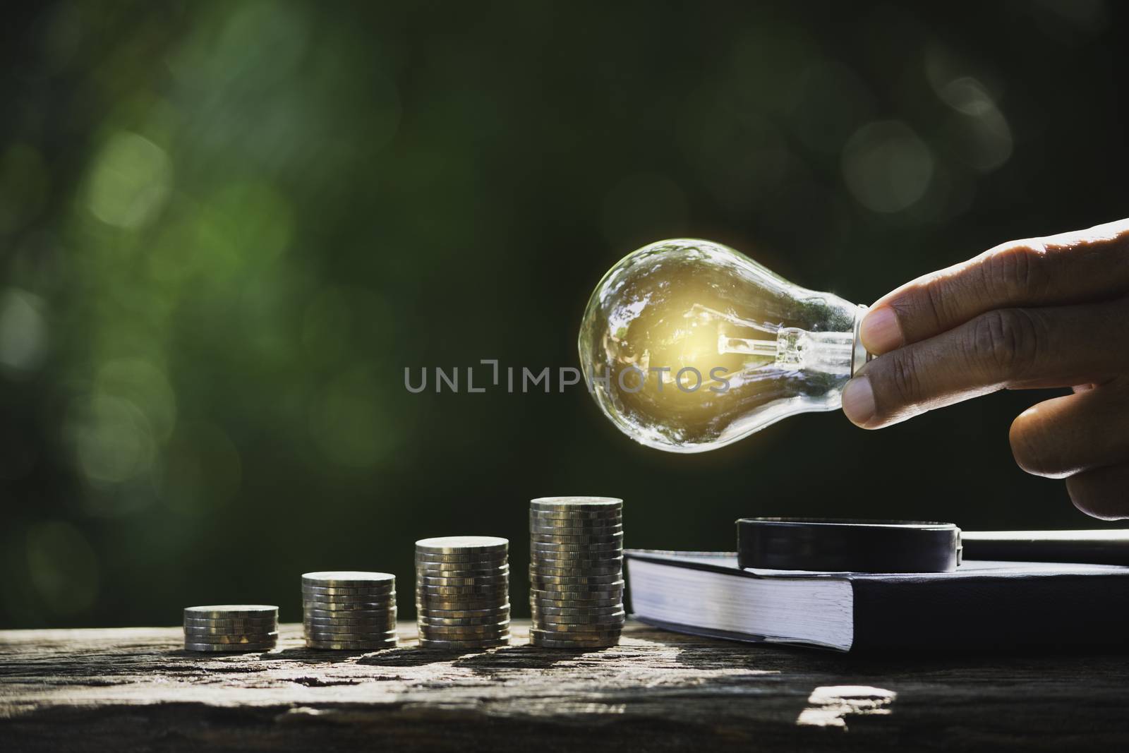 Hand of male holding a light bulb with stack of coins and copy s by kirisa99