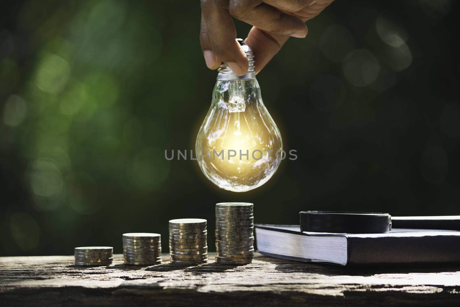 Hand of male holding a light bulb with stack of coins and copy s by kirisa99