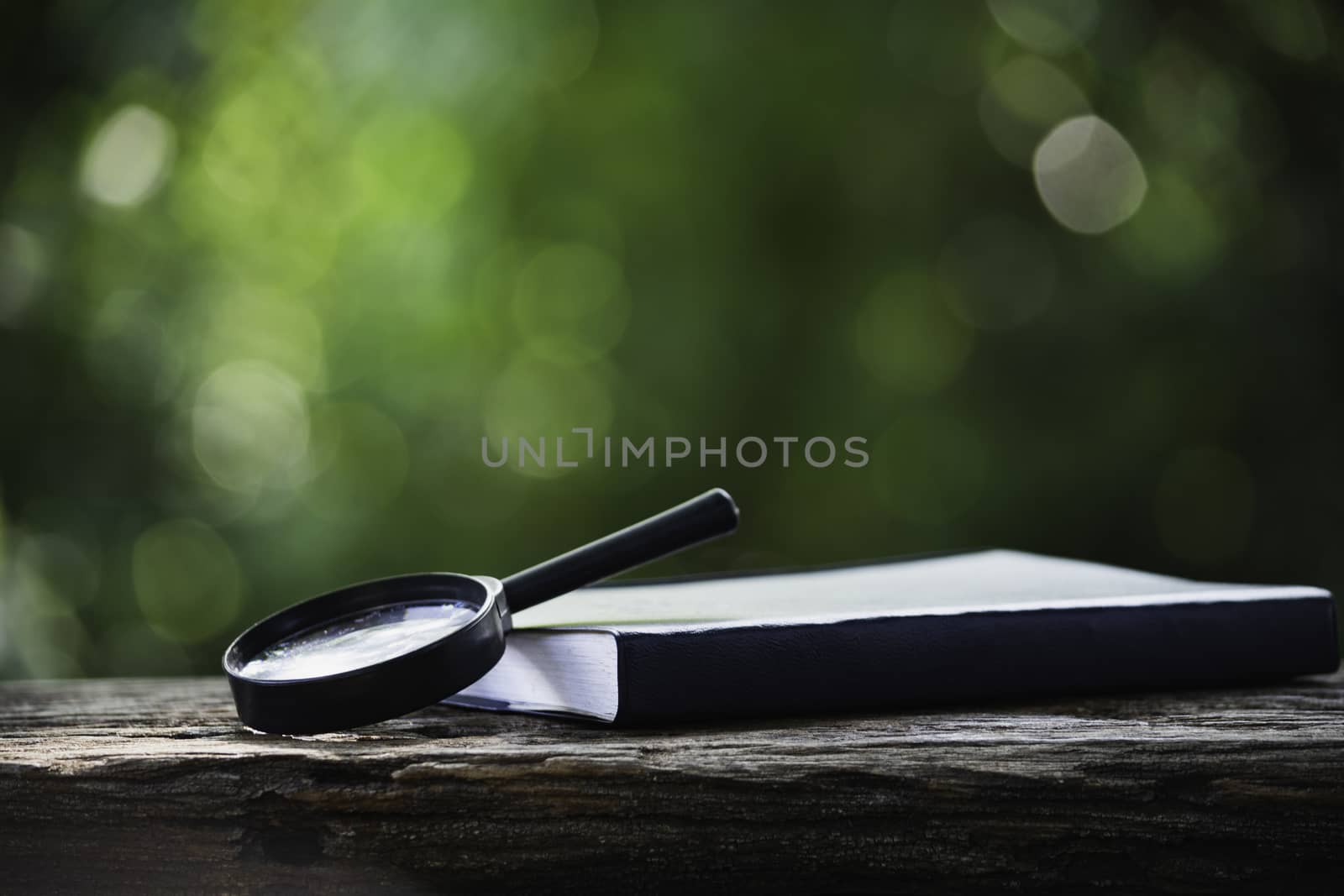 Magnifying glass and book on wooden table and copy space for insert text.
