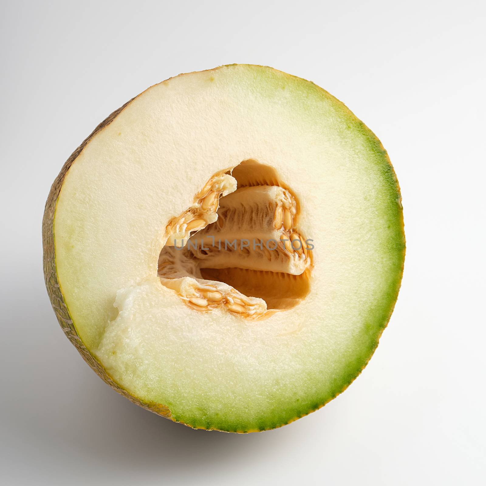 half of ripe yellow melon with seeds on white background, close up