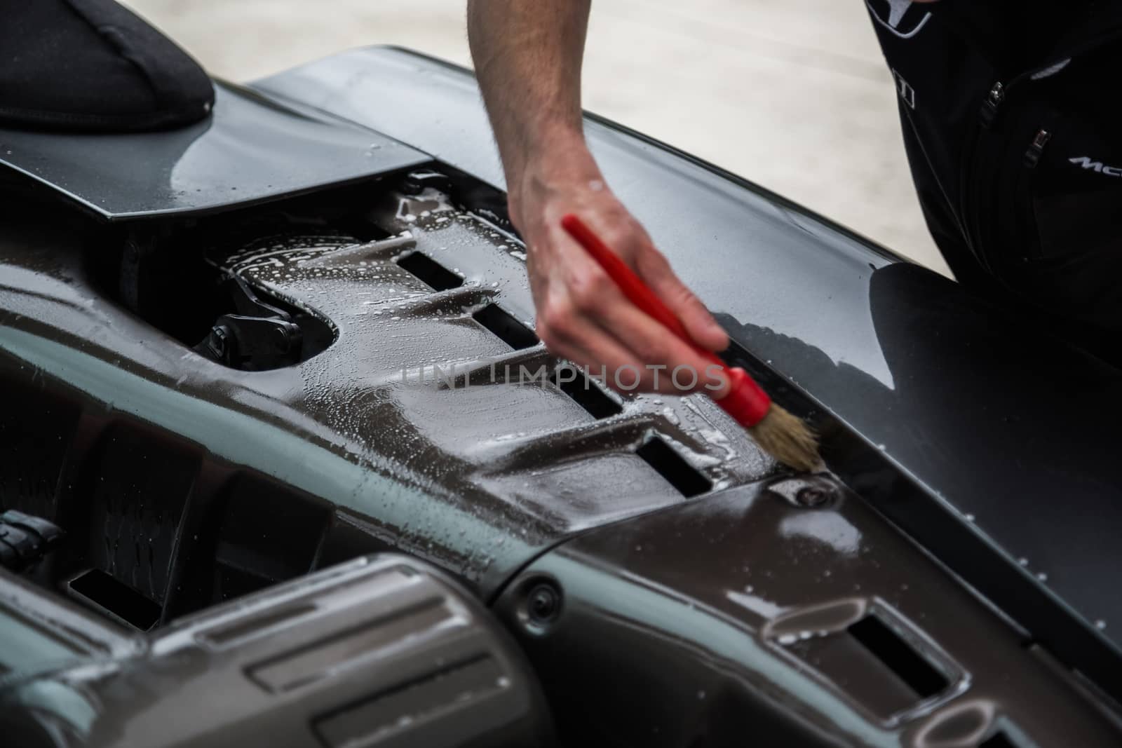 Detailer using a brush on a car during washing