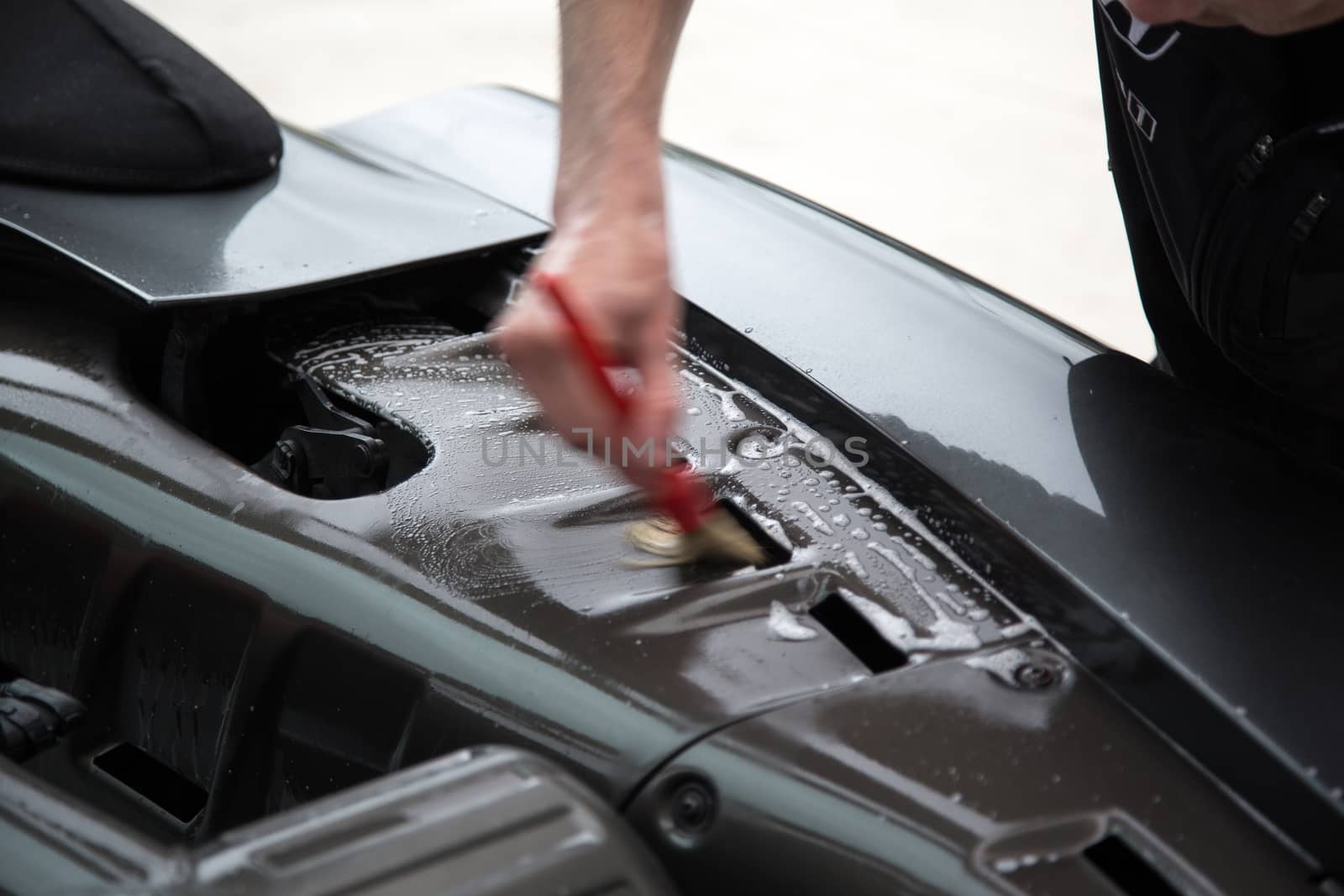 Detailer using a brush on a car during washing