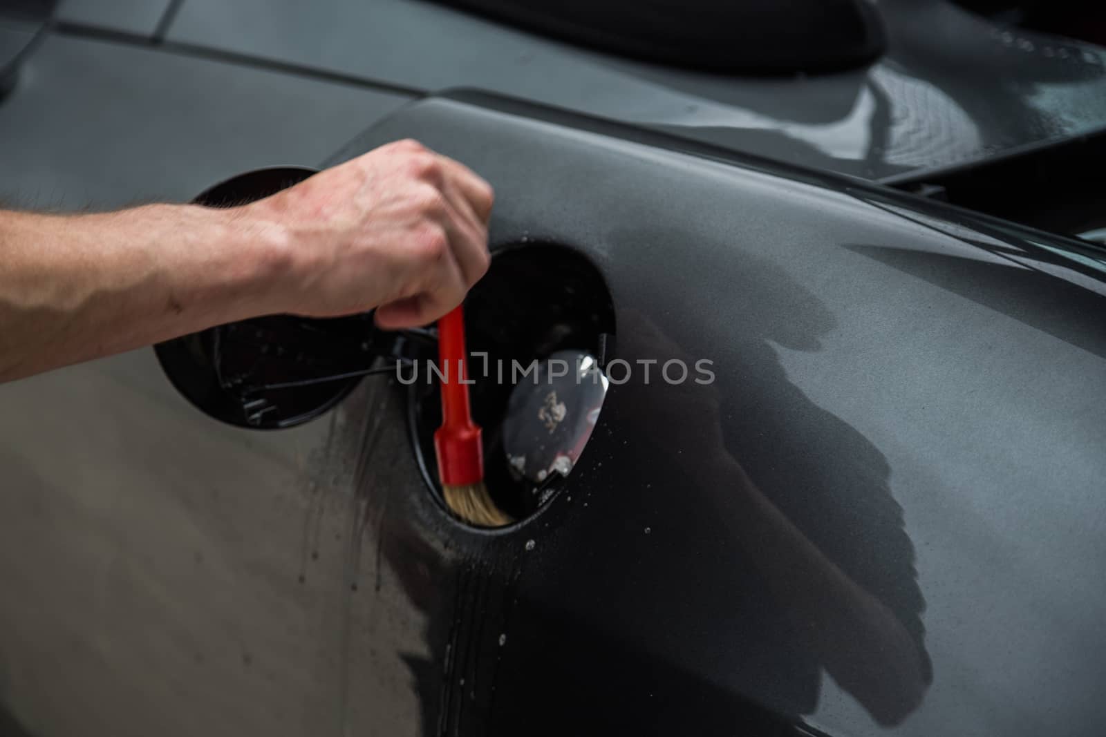 Detailer using a brush on a car during washing