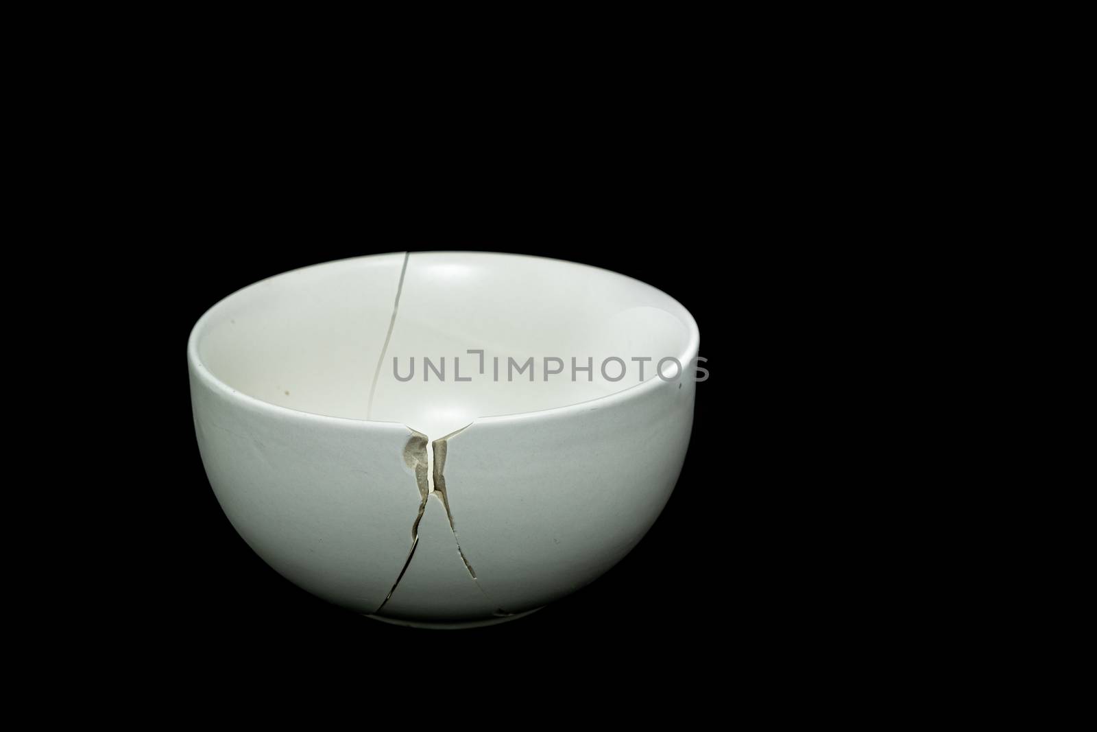 Pieces of broken white ceramic bowl on black background. Copyspace, place for text. Break, fragment. by peerapixs