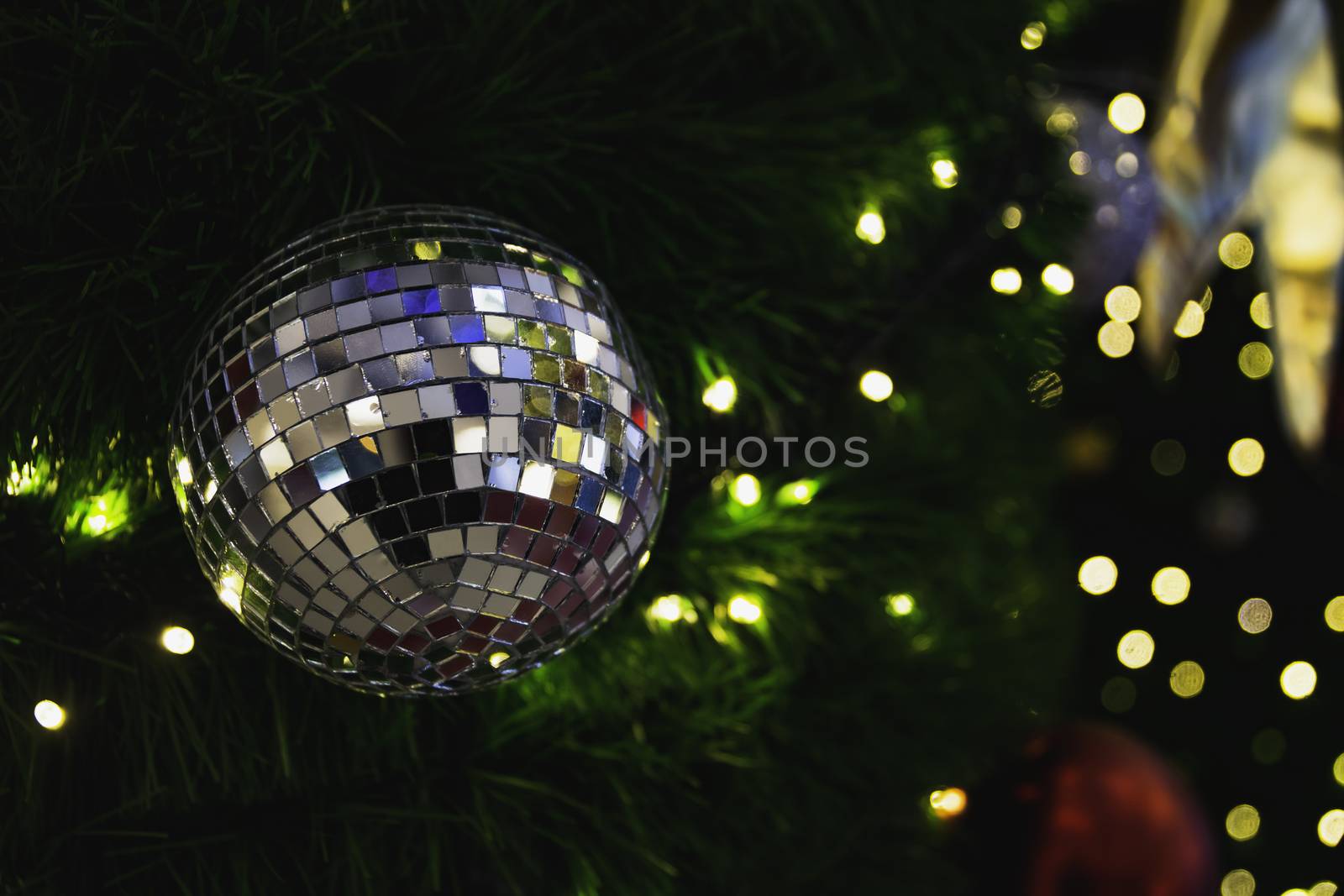 Christmas tree with Decorative lights and mirror ball on blurred background.