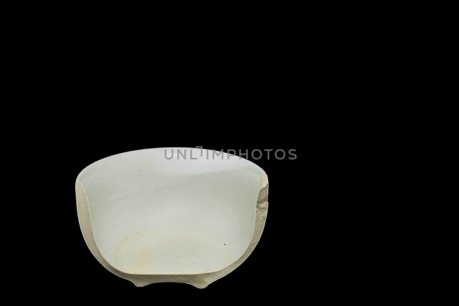 The Pieces of broken white ceramic bowl on black background. Copyspace, place for text. Break, fragment.