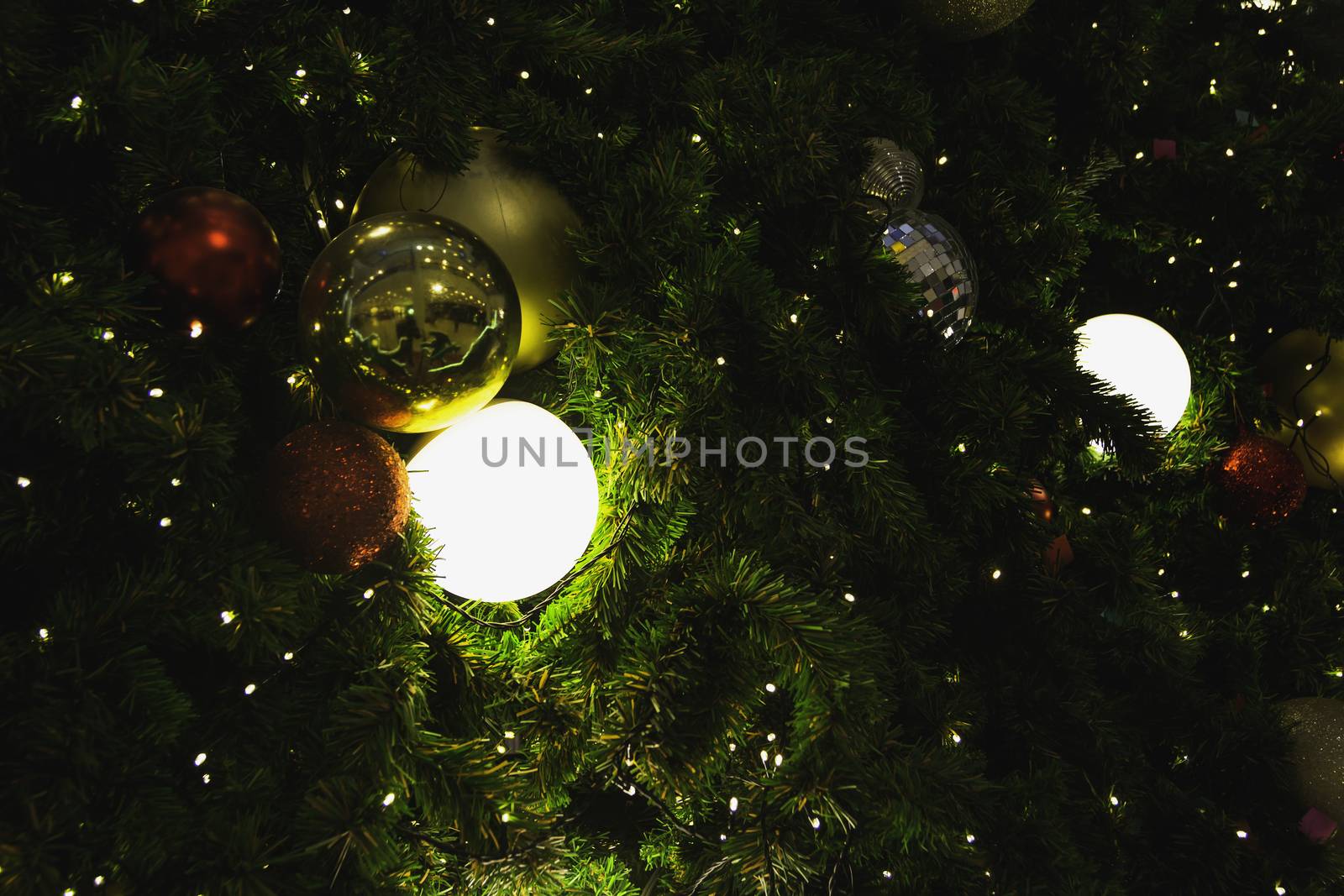 Christmas tree with Decorative lights and mirror ball on blurred background.