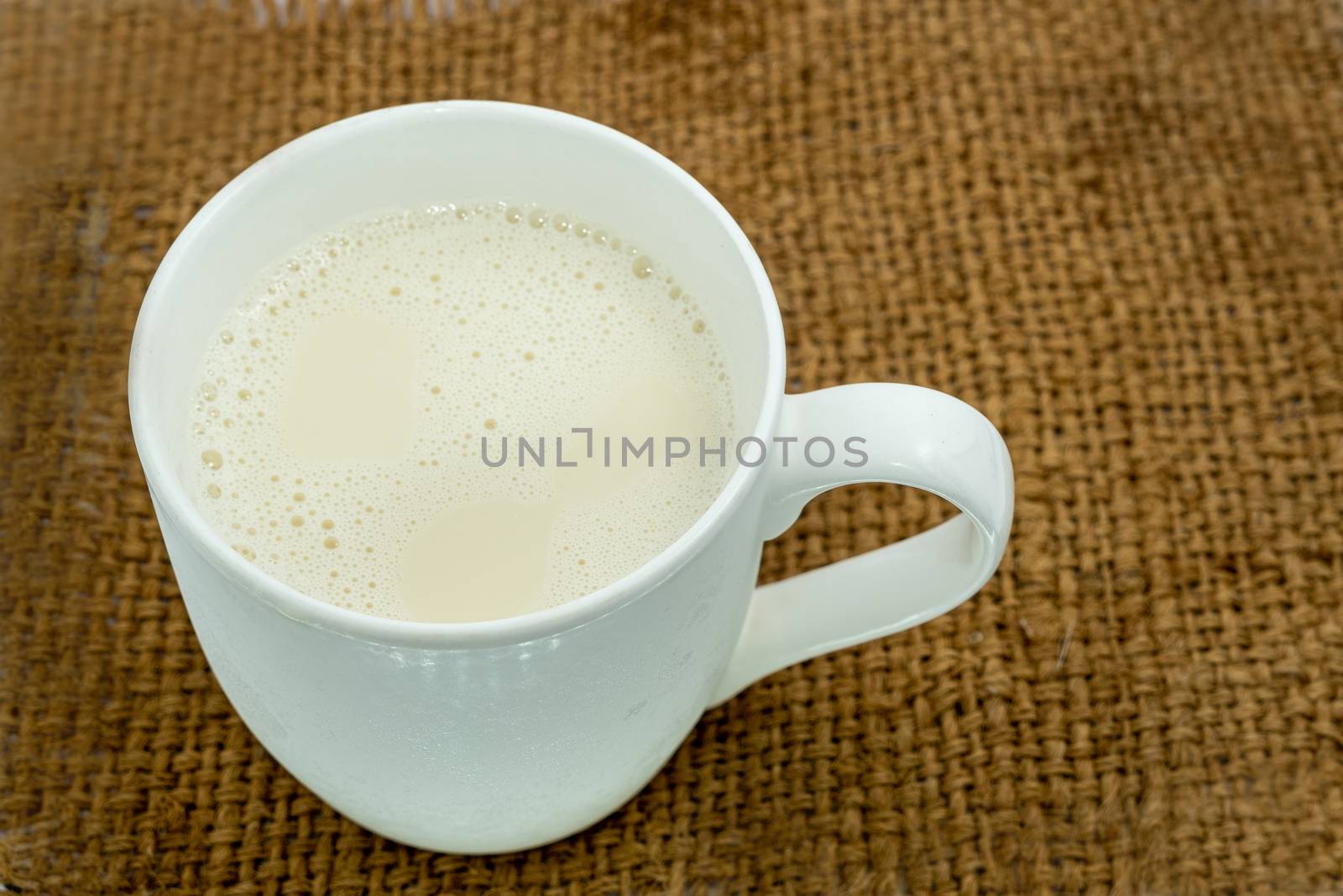 Bottle of milk and glass of milk on a wooden table on a blue background by peerapixs