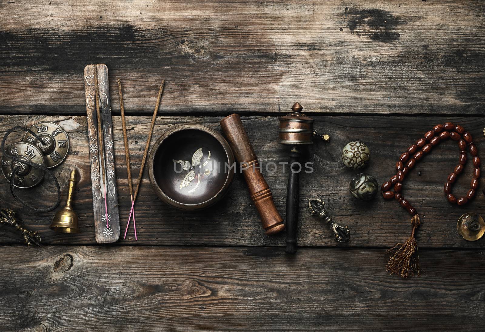 Copper singing bowl, prayer beads, prayer drum and other Tibetan religious objects for meditation and alternative medicine on a brown wooden background, copy space