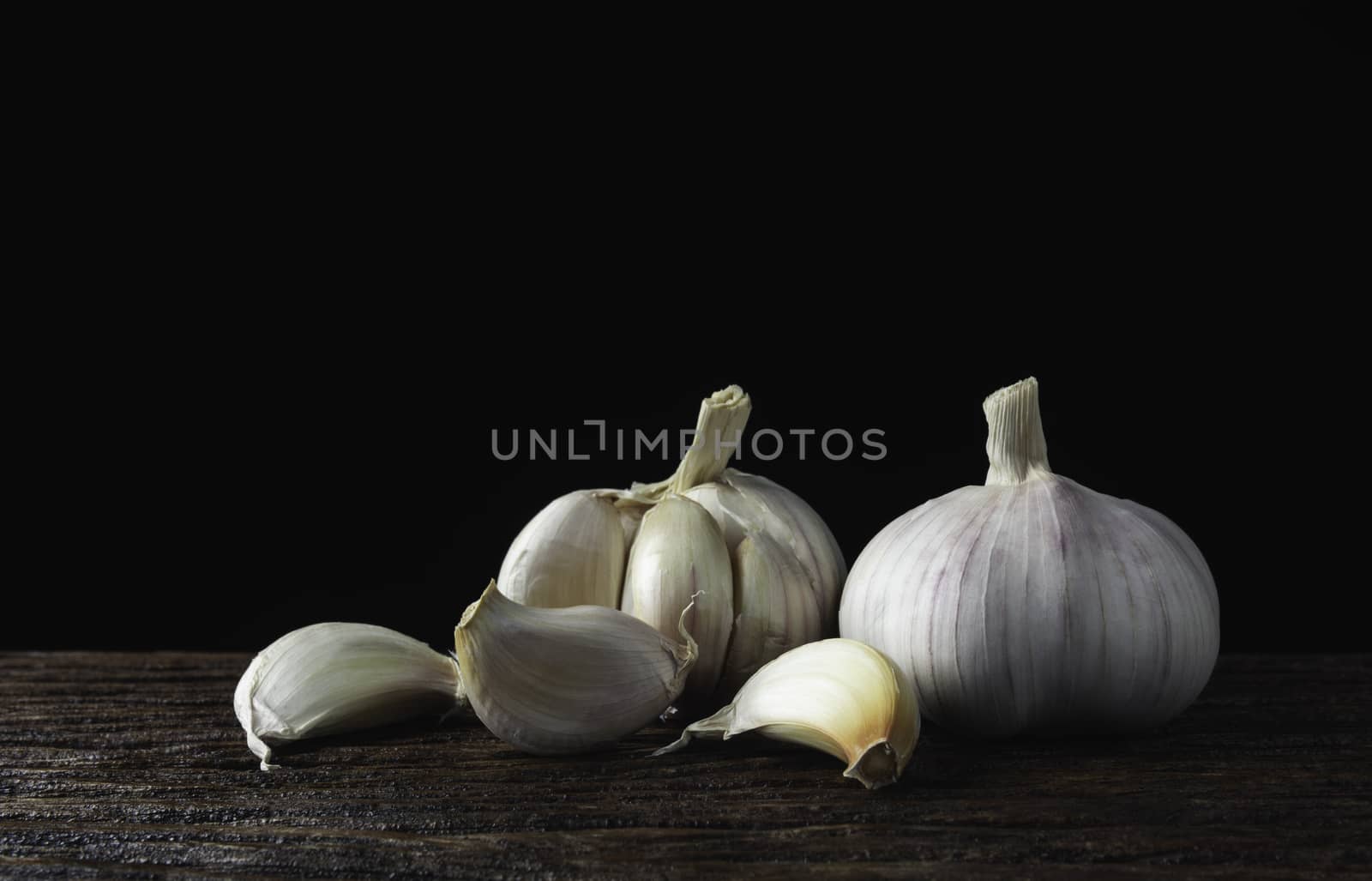 Fresh white garlic on wooden table with black background. Food and healthy concept. 