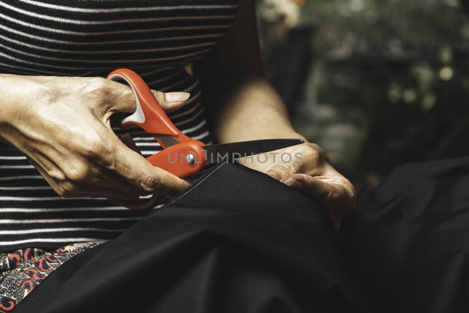 Woman cutting black fabric with scissors. Housework and lifestyle concept.