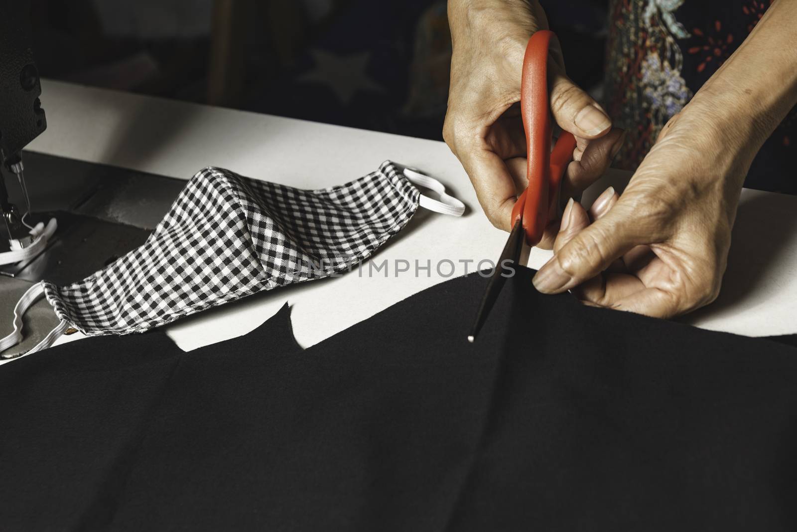 Woman cutting black fabric with scissors. Housework and lifestyle concept.