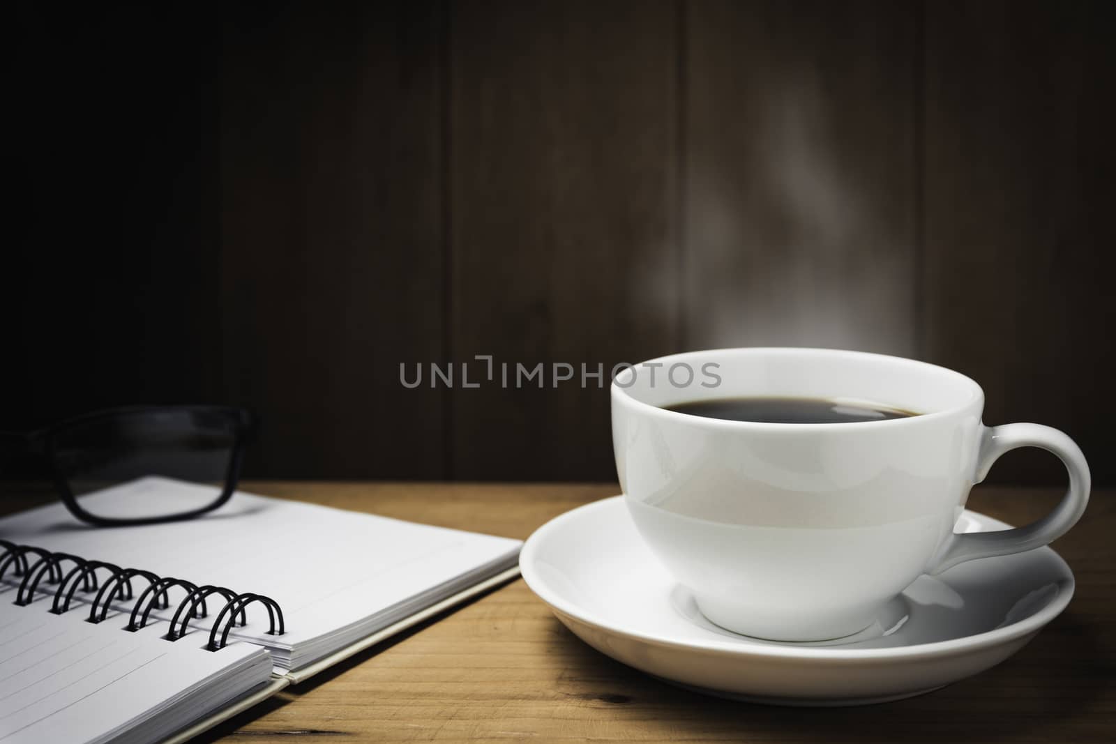Wooden table desk with coffee. Workspace with note book, pen and coffee cup on wooden background with copy space.