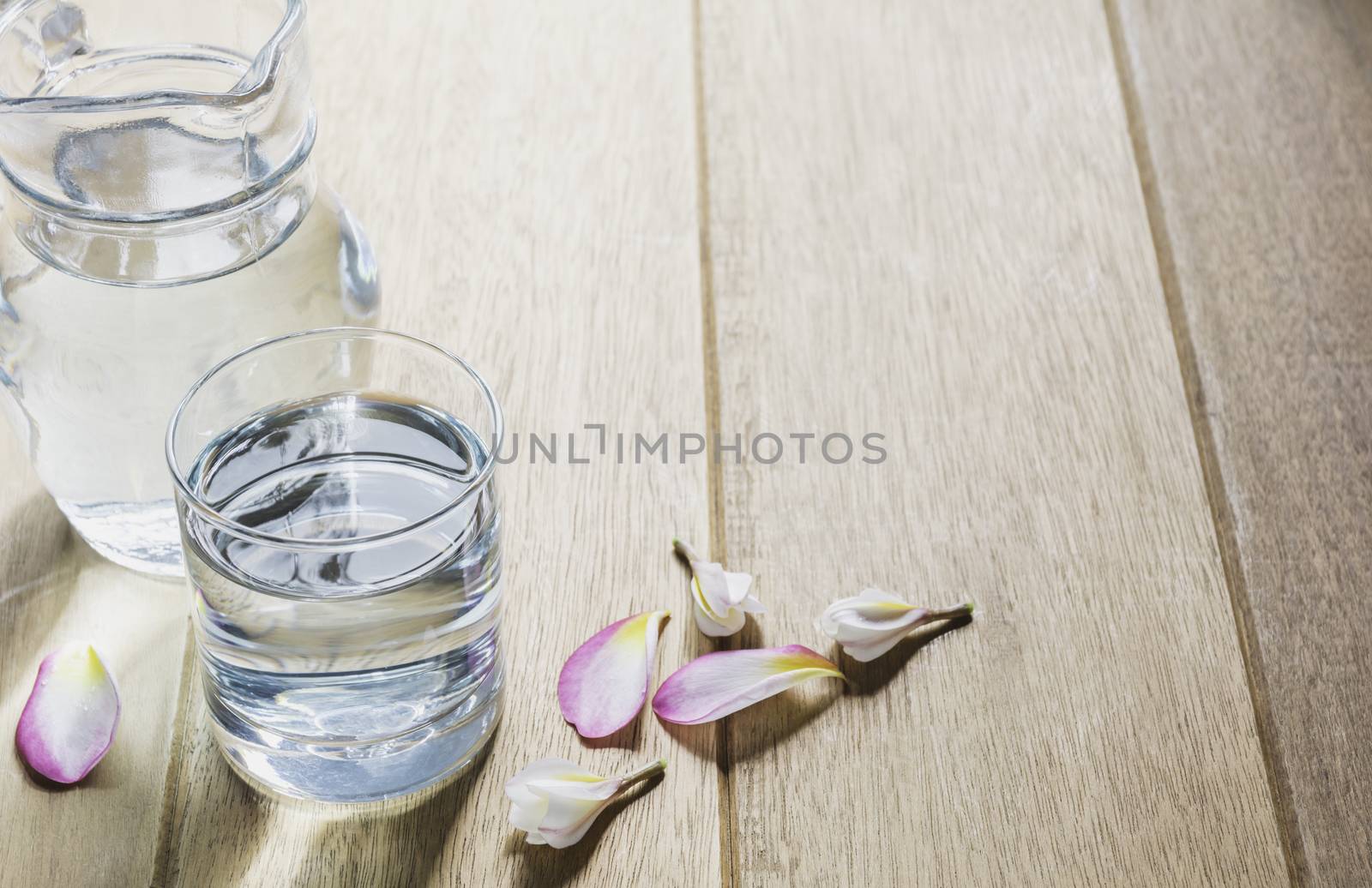 Water glass with glass jar on wooden table. Glass and clean drinking water with copy space.