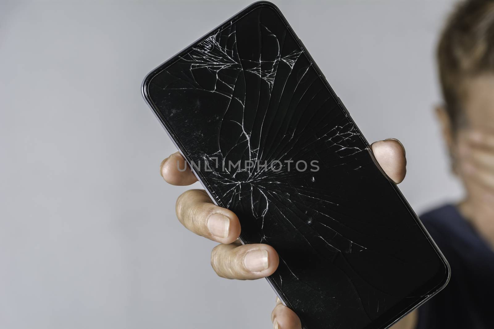 Woman holding a broken touch screen of smart phone on grey backg by kirisa99