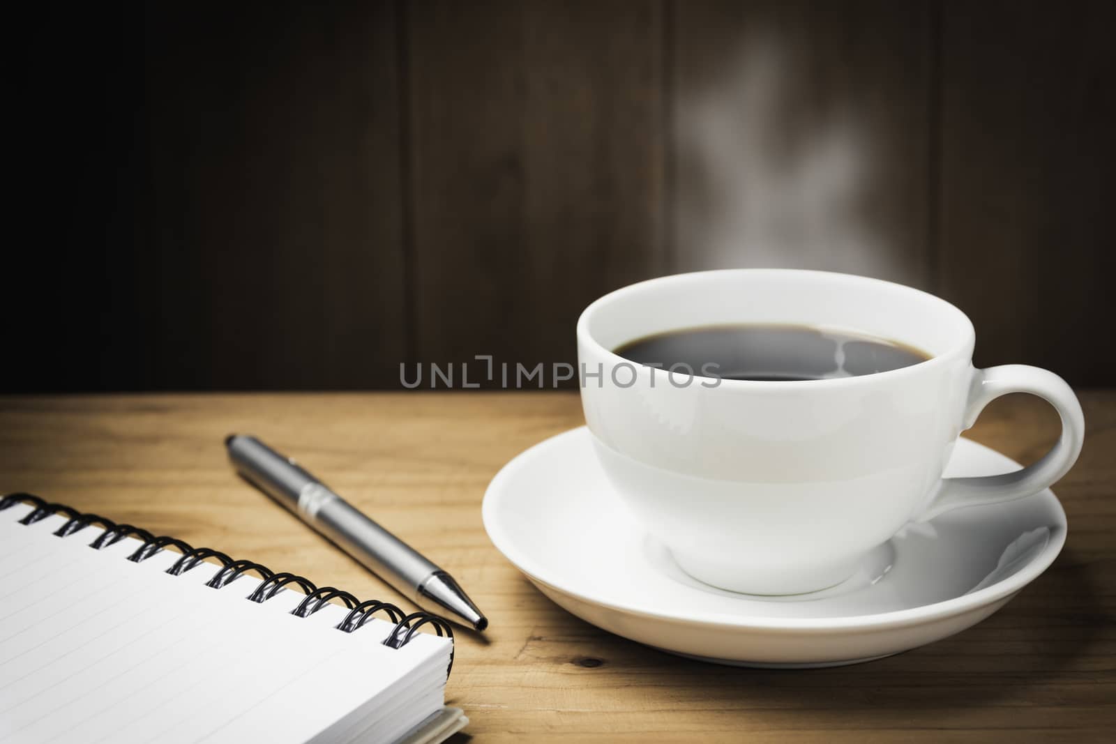 Wooden table desk with coffee. Workspace with note book, pen and coffee cup on wooden background with copy space.