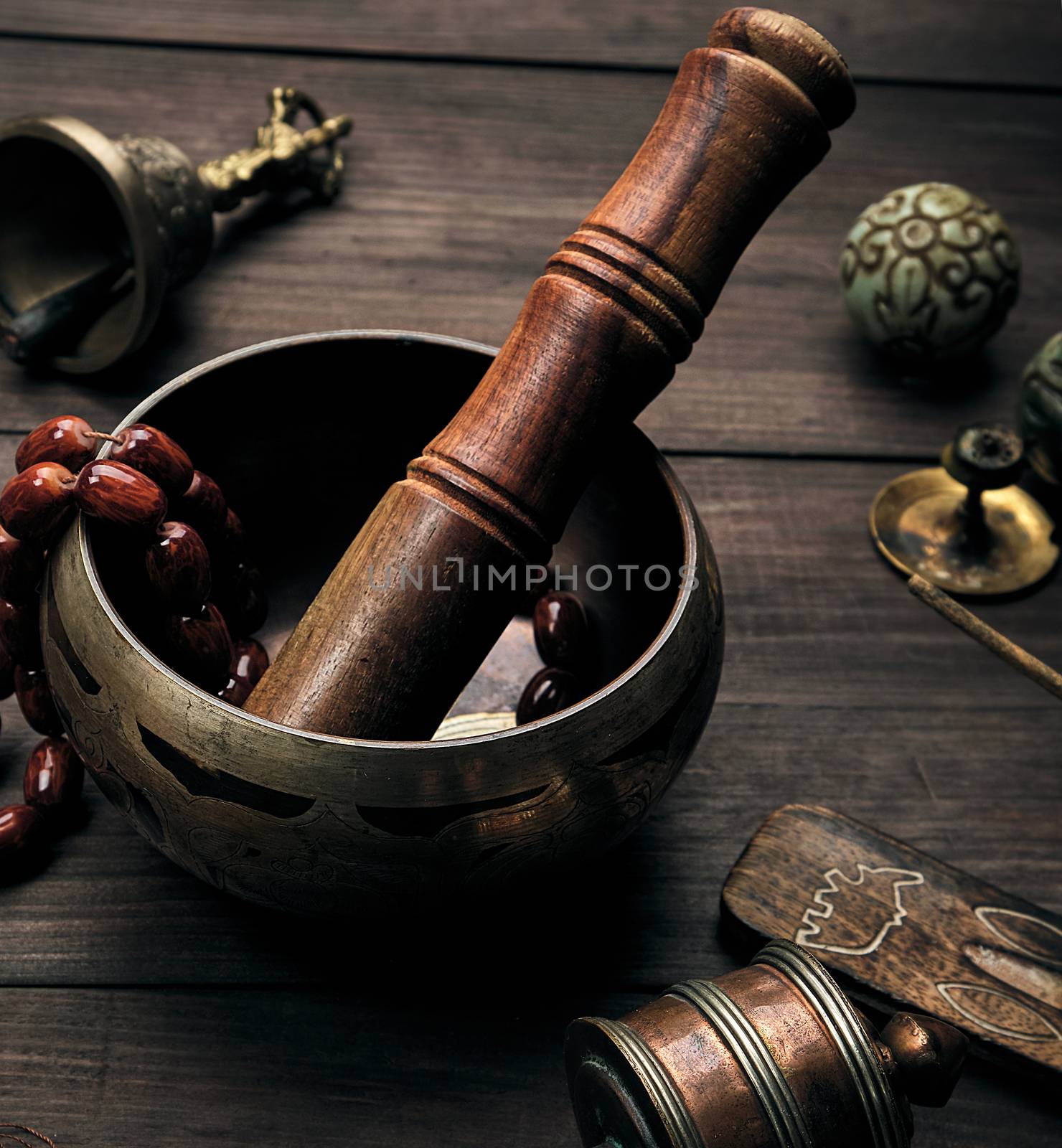 copper singing bowl and a wooden stick on a brown table  by ndanko
