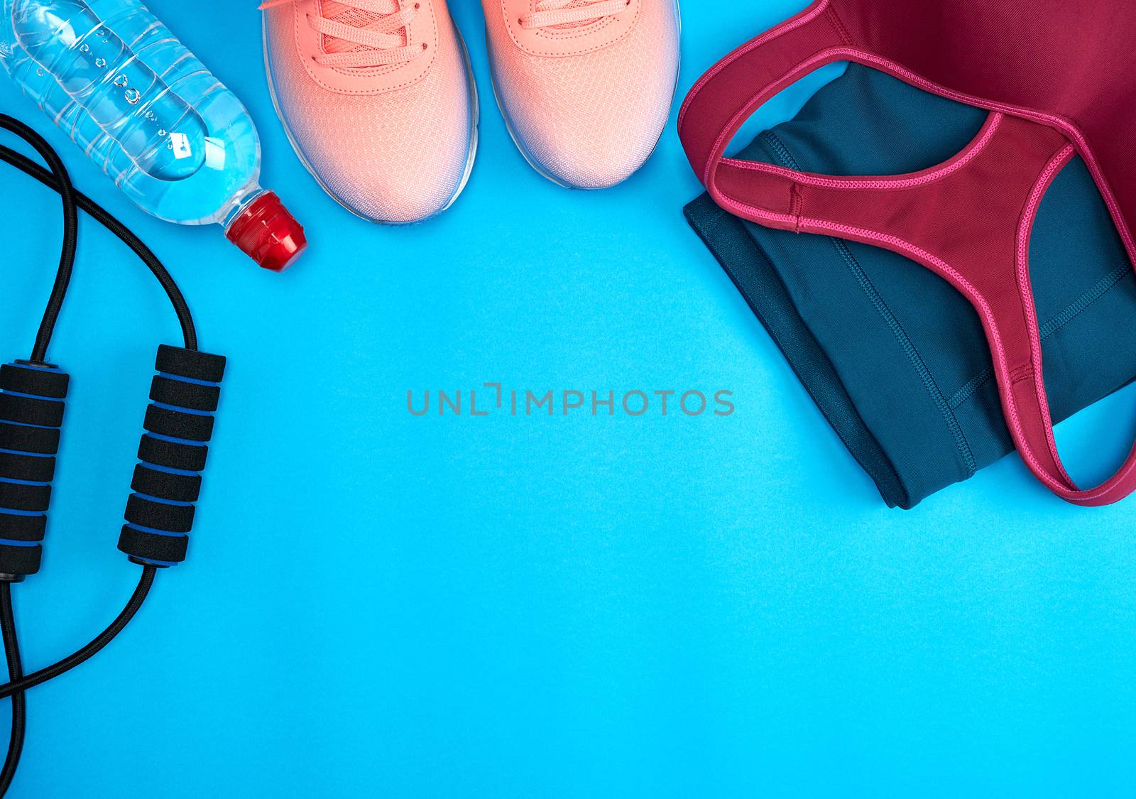 women's sportswear for active sports and pink sneakers on a blue background, top view
