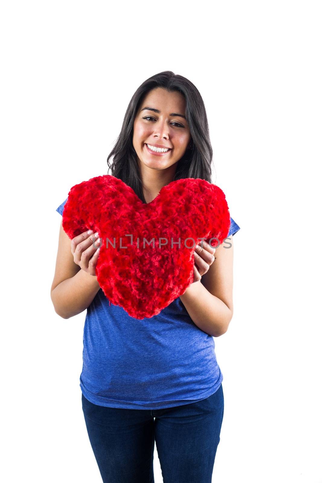 Smiling woman holding a heart shaped pillow against a white background