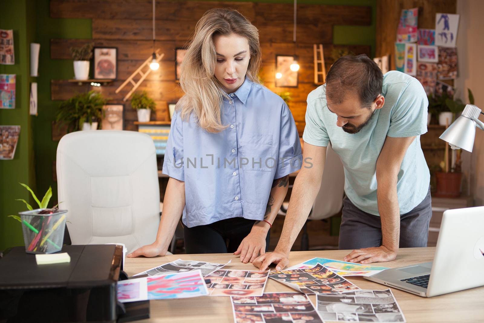 Focused female tailor and fashion designer sharing ideas in creative office.