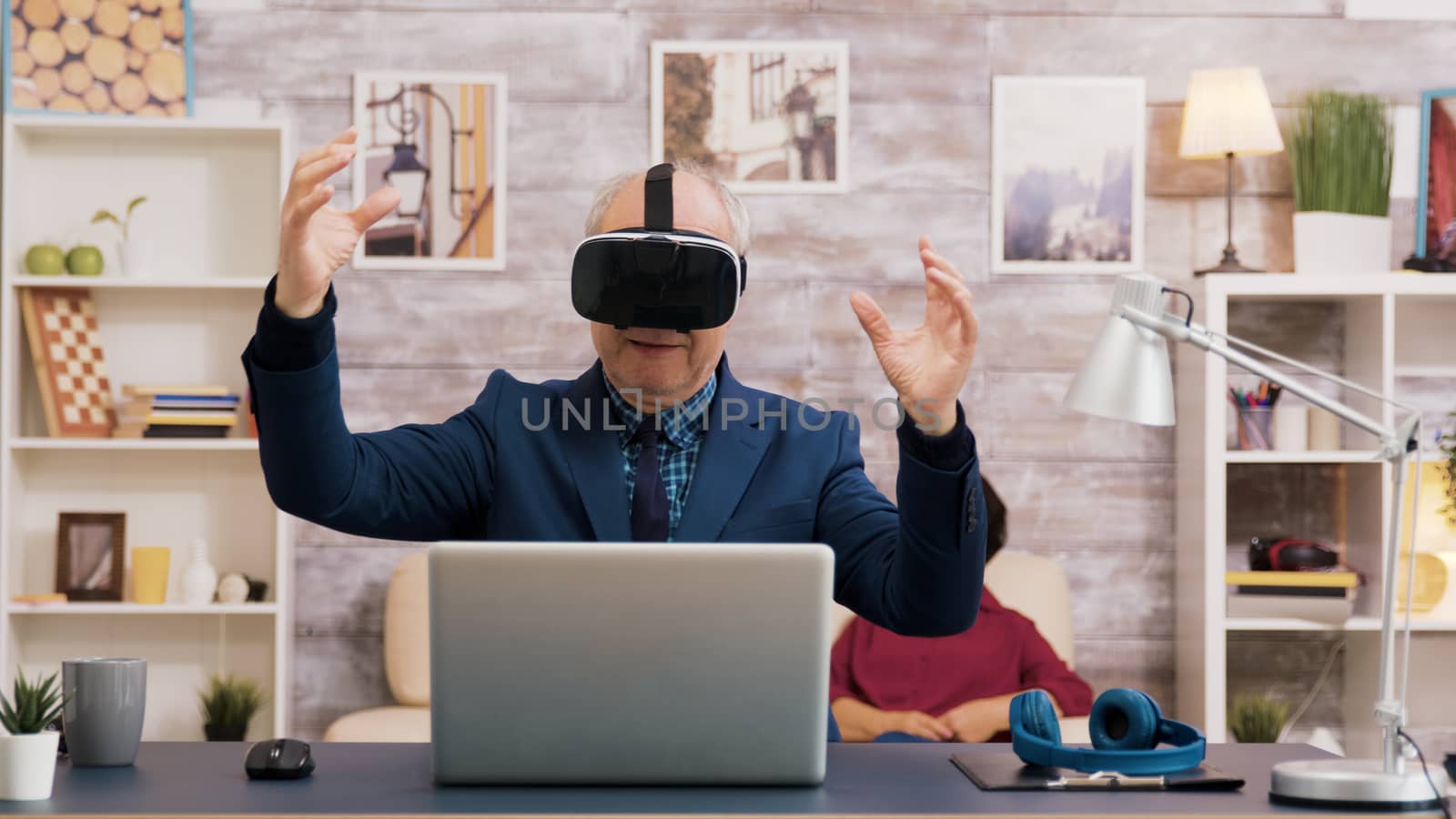 Senior man using virtual reality goggles in living room by DCStudio