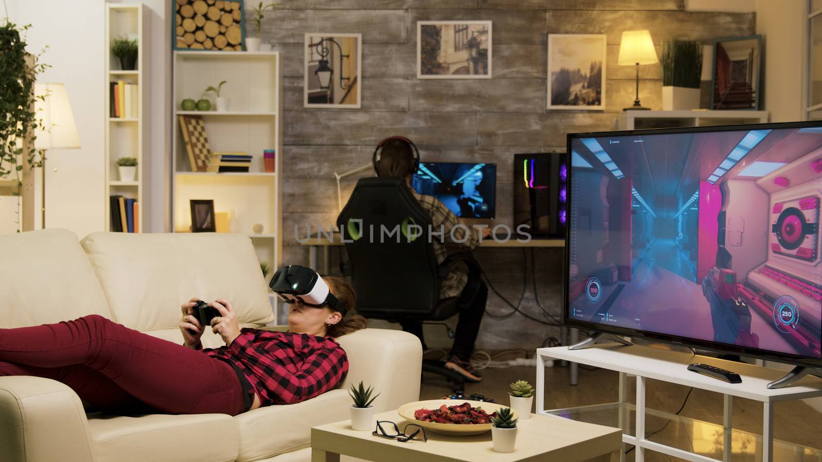 Woman lying on sofa playing video games using vr headset by DCStudio